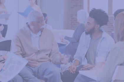 Young man in white coat talks to older man