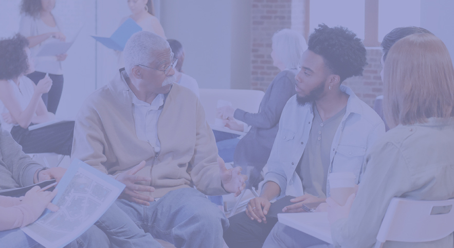 Young man in white coat talks to older man