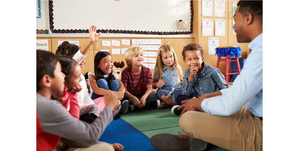 An early childhood education teacher sits in a circle with smiling students.