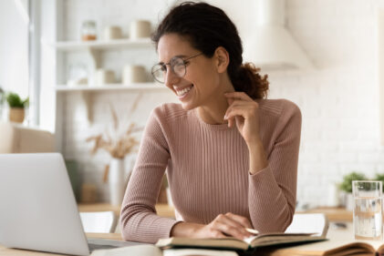 woman in sweater smiling at laptop
