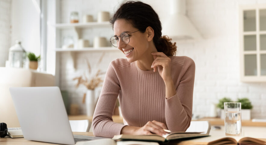 woman in sweater smiling at laptop