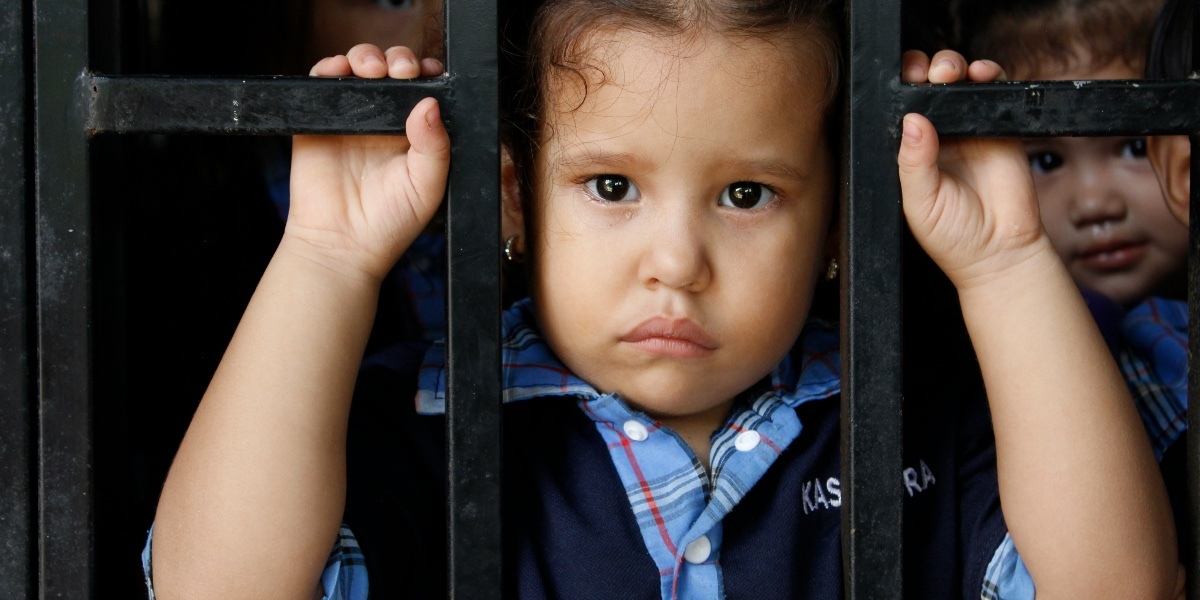 Toddler looking between metal bars.