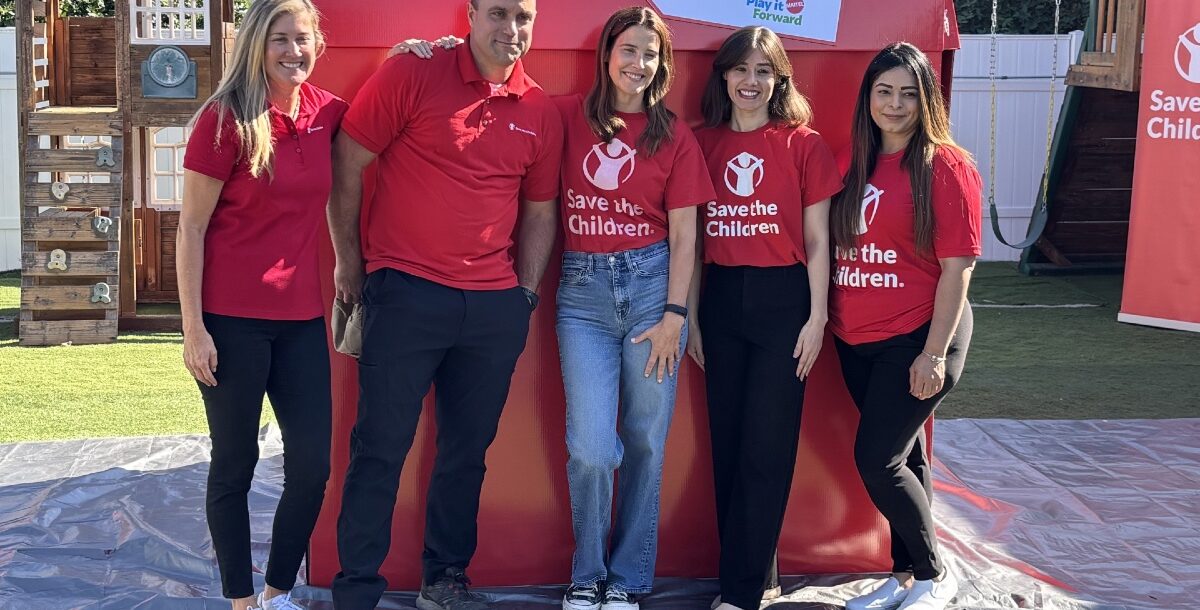 Volunteers, including actor Cobie Smulders, posing in front of a big red box.