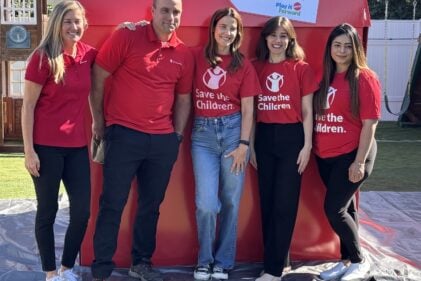 Volunteers, including actor Cobie Smulders, posing in front of a big red box.