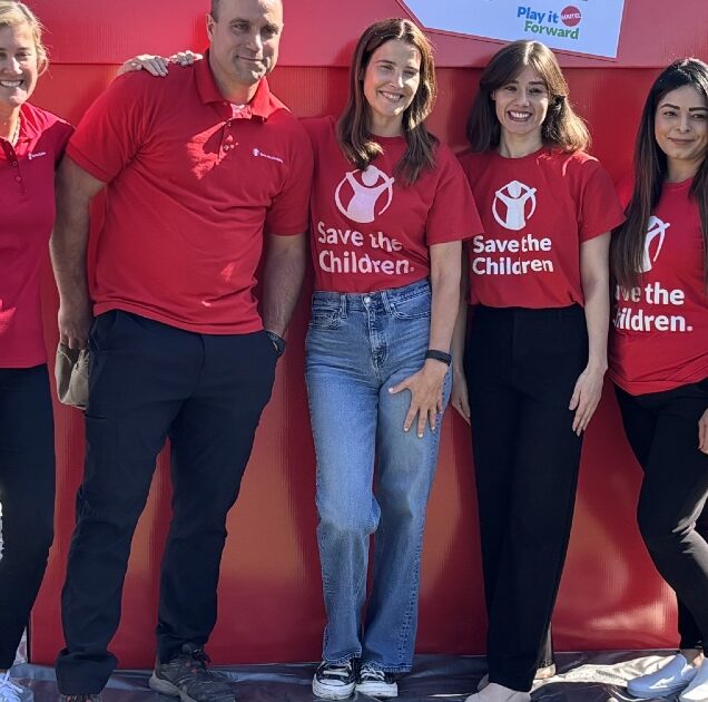 Volunteers, including actor Cobie Smulders, posing in front of a big red box.