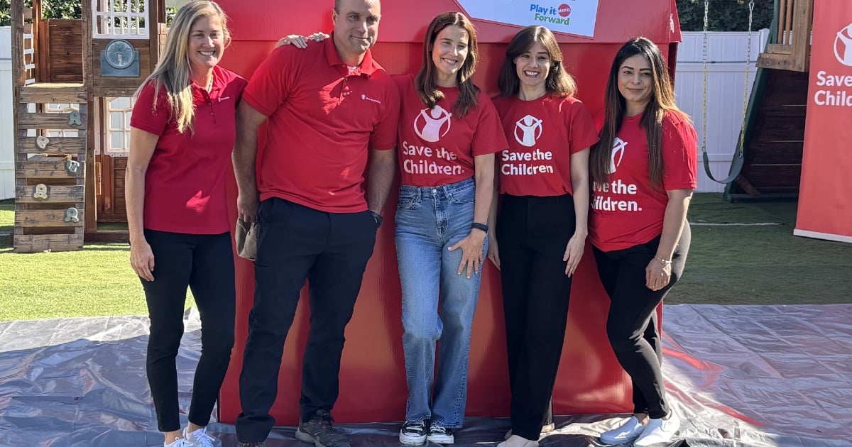 Volunteers, including actor Cobie Smulders, posing in front of a big red box.