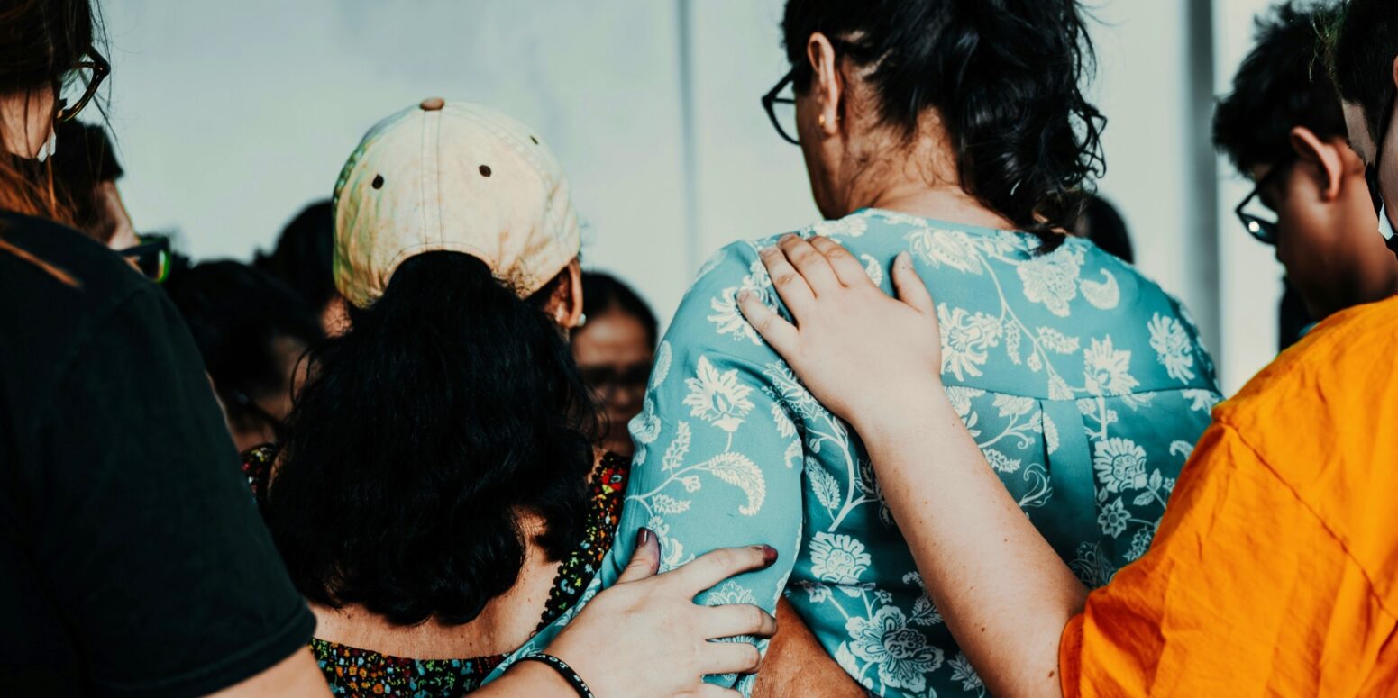 A picture from behind of a group of people with their arms on each other.