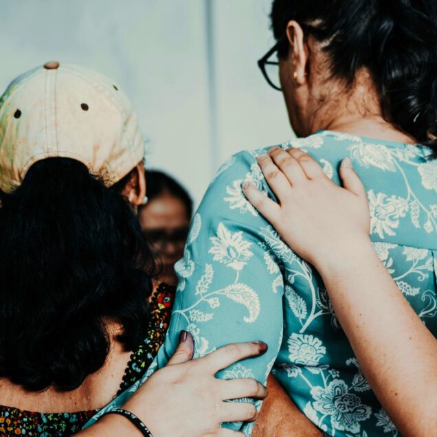 A picture from behind of a group of people with their arms on each other.