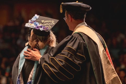 student in cap and gown at graduation with university president