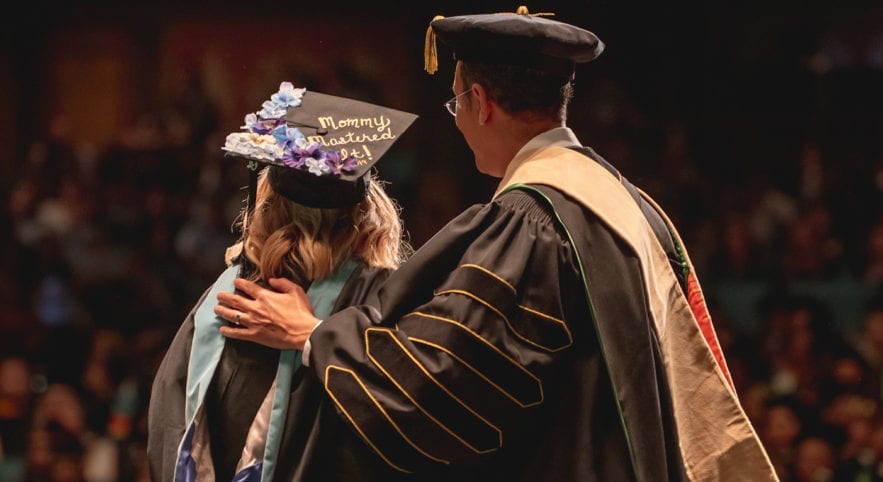 student in cap and gown at graduation with university president