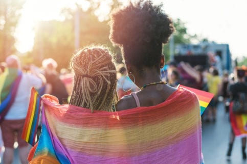 Two women wrapped in LGBTQ Flag