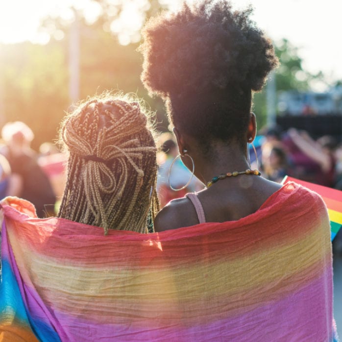 Two women wrapped in LGBTQ Flag