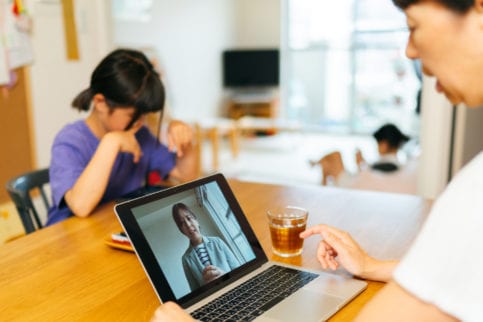 mother utilizing telehealth with child in background