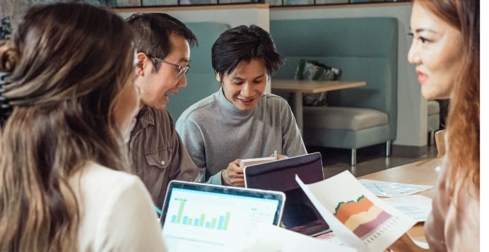 Group of asian students looking at charts and graphs