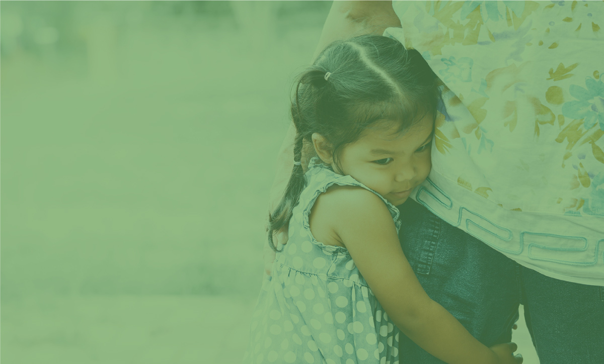 Small girl hugging the leg of an adult